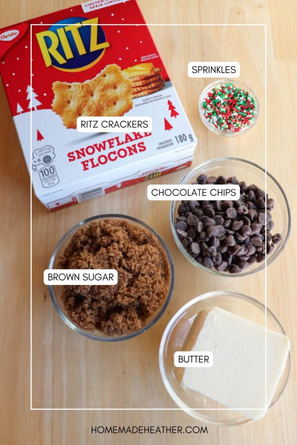 A box of Ritz crackers, bowls of brown sugar, chocolate chips, and sprinkles, plus a dish of butter are arranged on a wooden surface, labeled with their names.