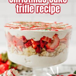A glass trifle dish filled with layers of whipped cream, sliced strawberries, and cake, topped with red and green sprinkles. Text on image: little debbie Christmas cake trifle recipe, so festive!.