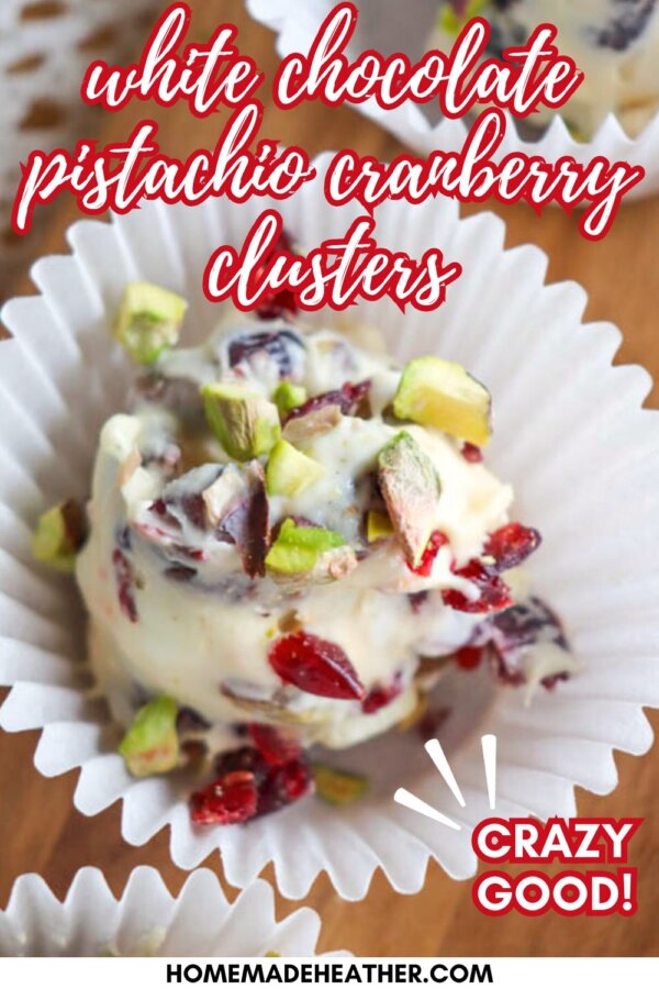 A white chocolate cluster with chopped pistachios and cranberries sits in a white paper cup on a wooden surface. Text reads: “white chocolate pistachio cranberry clusters” and “CRAZY GOOD!”.