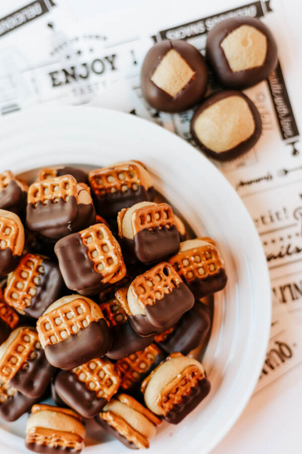 A white plate filled with small pretzel sandwiches dipped in chocolate, next to several round chocolate-dipped treats, all arranged on decorative paper with text.