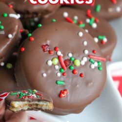 A close-up of chocolate-covered Ritz cracker cookies topped with colorful holiday sprinkles. One cookie has a bite taken out, showing a creamy filling. Text reads ritz cracker cookies and SO GOOD with homemadeheather.com at the bottom.