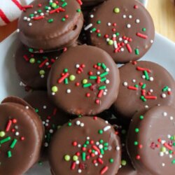 A plate of chocolate-covered Ritz cracker cookies topped with red, white, and green sprinkles. One cookie is bitten to show the inside layers. “Ritz Cracker cookies” and “homemadeheather.com” appear in the image.