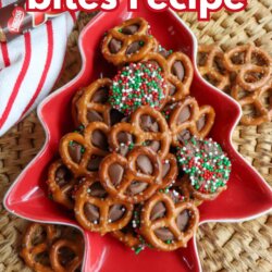 A red, tree-shaped dish holds Rolo pretzel bites topped with holiday sprinkles. The dish sits on a woven mat, with a red and white towel and extra pretzels nearby. Text reads “rolo pretzel bites recipe.”.