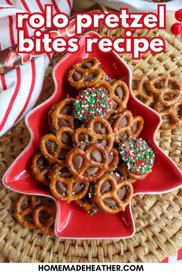 A red, tree-shaped dish holds Rolo pretzel bites topped with holiday sprinkles. The dish sits on a woven mat, with a red and white towel and extra pretzels nearby. Text reads “rolo pretzel bites recipe.”.