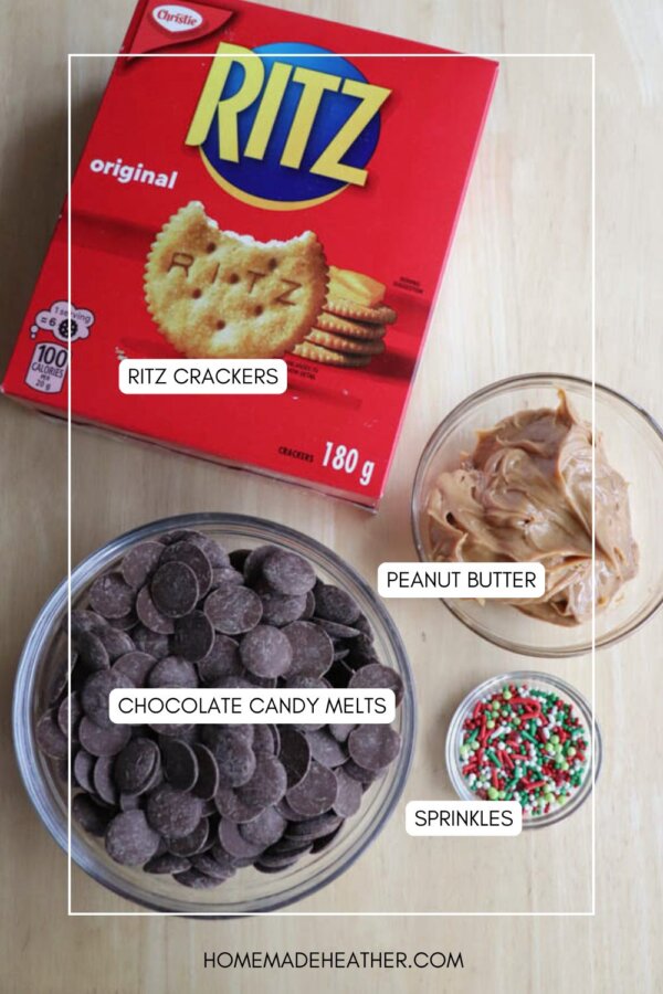 A top-down view of ingredients for a snack: a box of Ritz crackers, a bowl of chocolate candy melts, a bowl of peanut butter, and a small bowl of colorful sprinkles on a wooden surface.