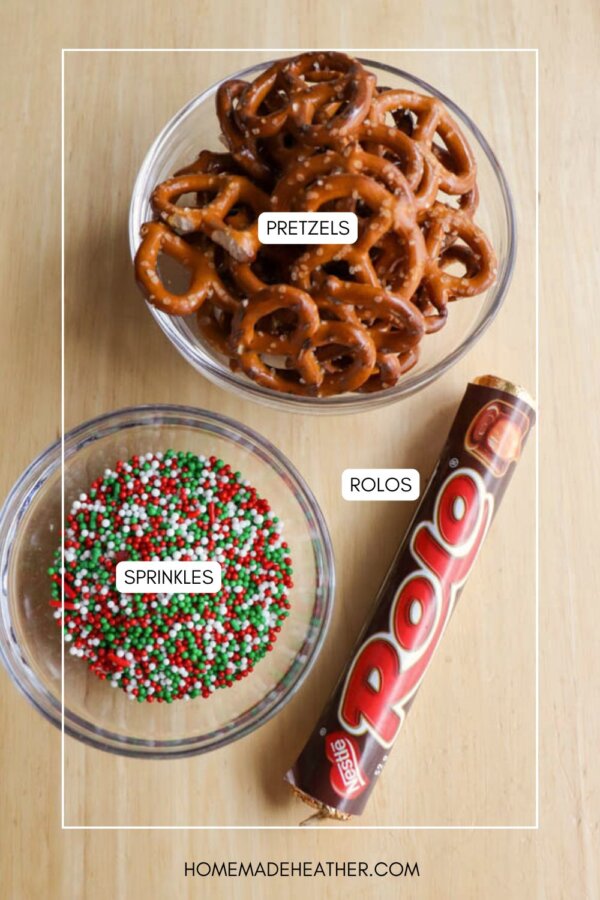 A bowl of pretzels, a bowl of red, white, and green sprinkles, and a roll of Rolo chocolates are arranged on a light wooden surface. Each item is labeled with text.