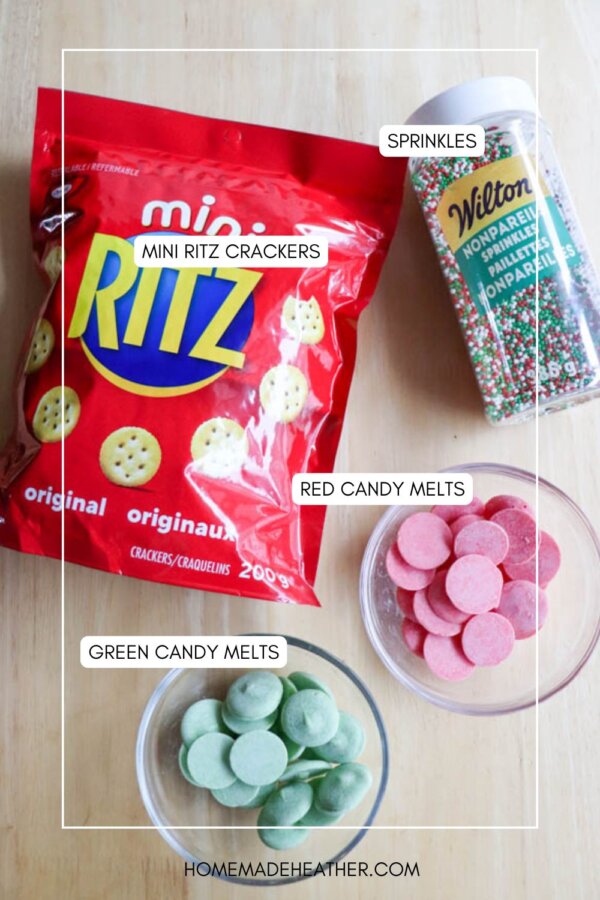 A bag of Mini Ritz crackers, a container of Wilton sprinkles, a bowl of red candy melts, and a bowl of green candy melts are arranged on a light-colored surface.