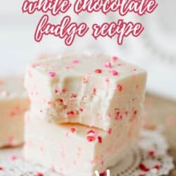 Two pieces of white chocolate fudge with pink and red sprinkles are stacked on a doily, with text reading Valentines Day white chocolate fudge recipe and So good! at the bottom.