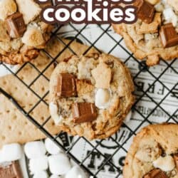 A cooling rack holds several smores cookies topped with chunks of chocolate, graham crackers, and mini marshmallows. Text reads the best smores cookies and so good, with ingredients displayed nearby.