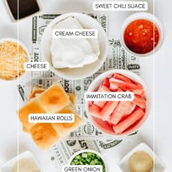 Top view of ingredients for a recipe, including bowls of cream cheese, shredded cheese, sweet chili sauce, imitation crab, green onion, Hawaiian rolls, soy sauce, and seasonings, each labeled with text.