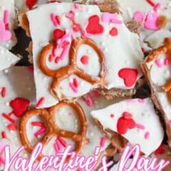 Close-up of Valentineโs Day pretzel toffee topped with white chocolate, pretzels, pink and red heart sprinkles, and confetti sprinkles. Text reads Valentineโs Day Pretzel Toffee homemadetheather.com.