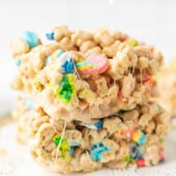 Stacked Lucky Charms and Rice Krispies treats with colorful marshmallows, displayed on a lace doily, with text reading Lucky Charms rice krispies and homemadeheather.com above and below.
