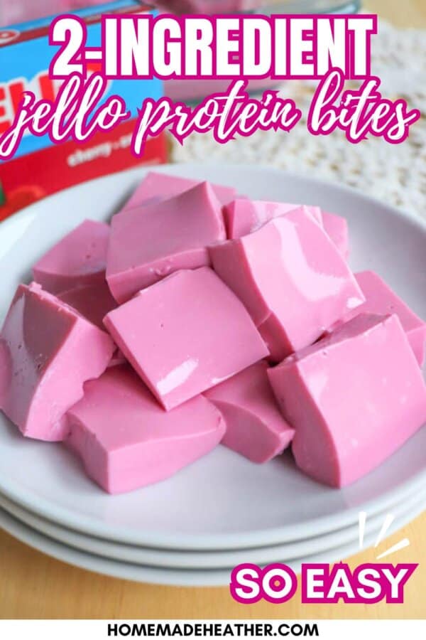 A plate of pink Jello protein bites cut into squares, stacked on white plates. Text on the image reads, 2-ingredient Jello protein bites, so easy. Website URL: homemadeheather.com.