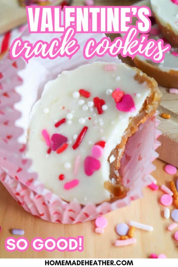 A close-up of a Valentines-themed cookie with white icing and colorful heart-shaped sprinkles in a pink cupcake liner. Text reads โValentineโs crack cookiesโ and โSo good!โ with the website homemadeheather.com at the bottom.