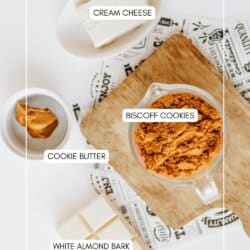Top-down view of labeled ingredients for a biscoff cookie butter delight on a white surface: cream cheese, crushed Biscoff cookies in a glass bowl, cookie butter in a small dish, and white almond bark squares on a wooden board.
