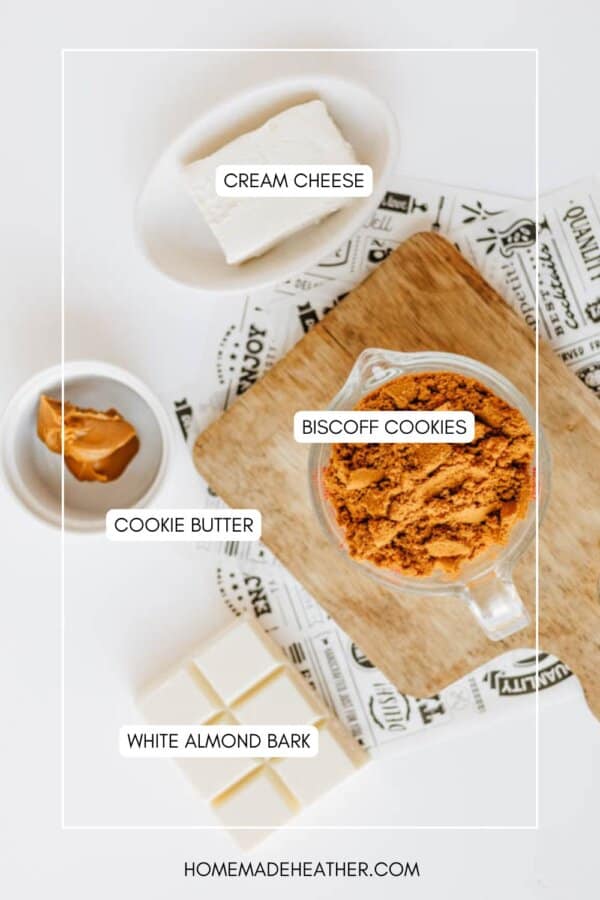 Top-down view of labeled ingredients for a biscoff cookie butter delight on a white surface: cream cheese, crushed Biscoff cookies in a glass bowl, cookie butter in a small dish, and white almond bark squares on a wooden board.