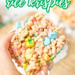 A hand holds a colorful Rice Krispies treat made with Lucky Charms cereal. Bold text at the top reads Lucky Charms rice krispies and SO EASY! is highlighted at the bottom, with homemadeheather.com below.
