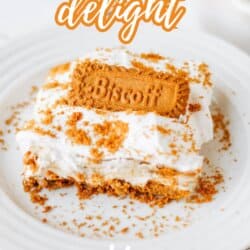A dessert made with layers of whipped cream and crumbled Biscoff cookies sits on a white plate, topped with a whole cookie. Text on image reads: “Biscoff Cookie Butter Delight, So Easy, homemadeheather.com.”.