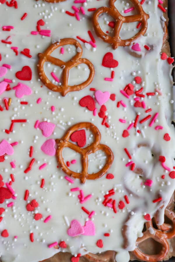 Close-up of white chocolate bark topped with pretzel twists and decorated with red, pink, and white heart-shaped and sprinkle toppings.