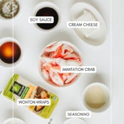 Top-down view of ingredients for crab rangoon: soy sauce, cream cheese, imitation crab, wonton wraps, seasoning, and a small bowl of sauce, all labeled and arranged on a white surface.