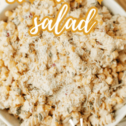 A bowl of creamy street corn salad topped with grated cheese, garnished with herbs. Text on image reads “street corn salad” and “so good!” with the website homemadetheather.com at the bottom.