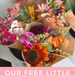Bouquets of colorful fresh flowers wrapped in brown paper are displayed in a metal bucket. A pink sign below reads, Our Free Little Flower Stand homemadheather.com.