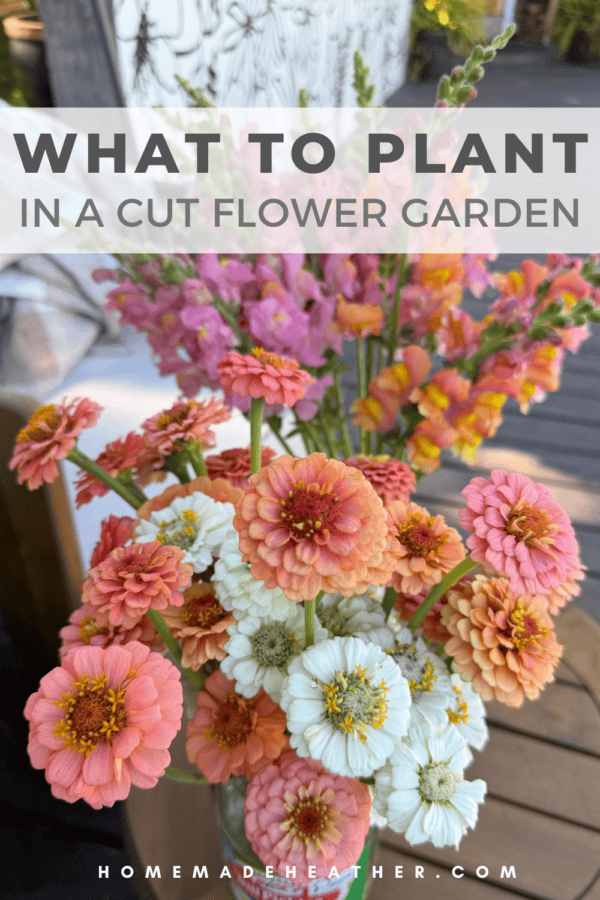 A bouquet of pink, white, and orange zinnias and snapdragons sits on a wooden table. Text reads: What to plant in a cut flower garden. homemadeheather.com.